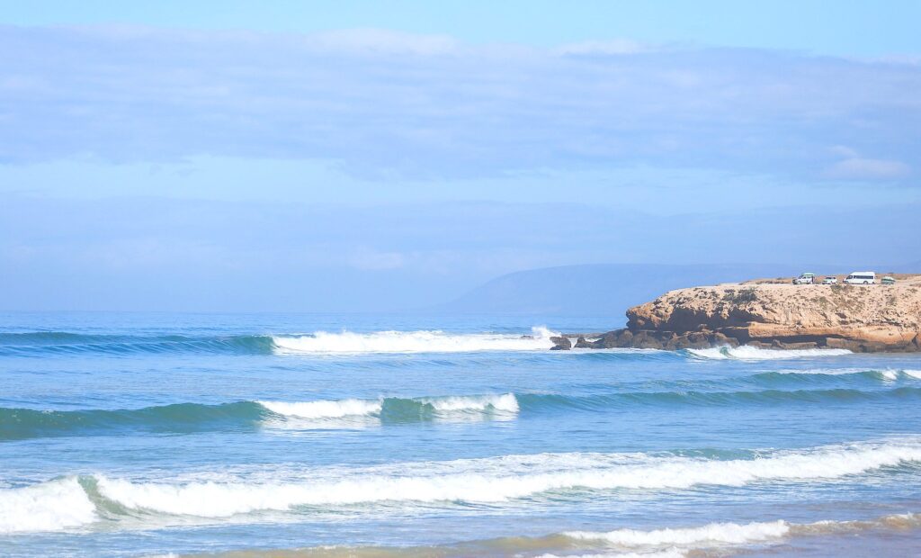 Surf lessons in Tamraght, Morocco, with beginner and expert surfers enjoying the waves.